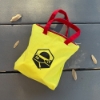 Yellow zippered Catan carry bag with red handles and black Catan mountain and sun logo, shown outdoors on a gray deck.