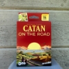 CATAN - On the Road in front of a paneled wood wall